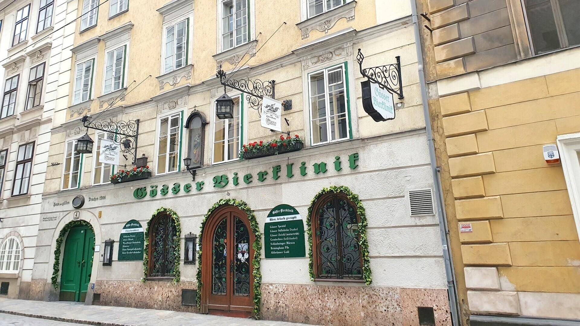 Detailansicht eines gepflegten historischen Gebäudes mit dekorativen Elementen, großen Fenstern und grünen Türen.