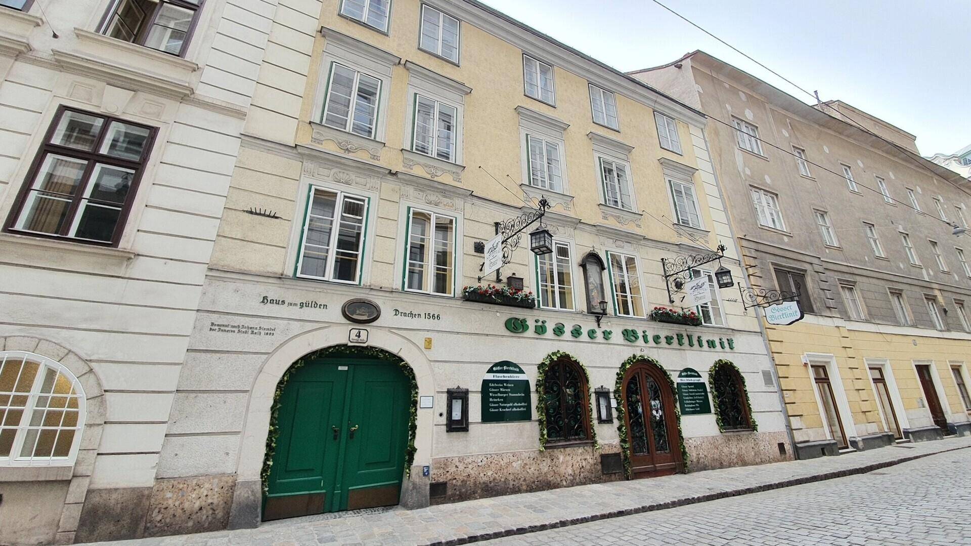 Ansicht eines charmanten alten Gebäudes mit gelber Fassade, vielen Fenstern und markanten grünen Türen in der Stadt.