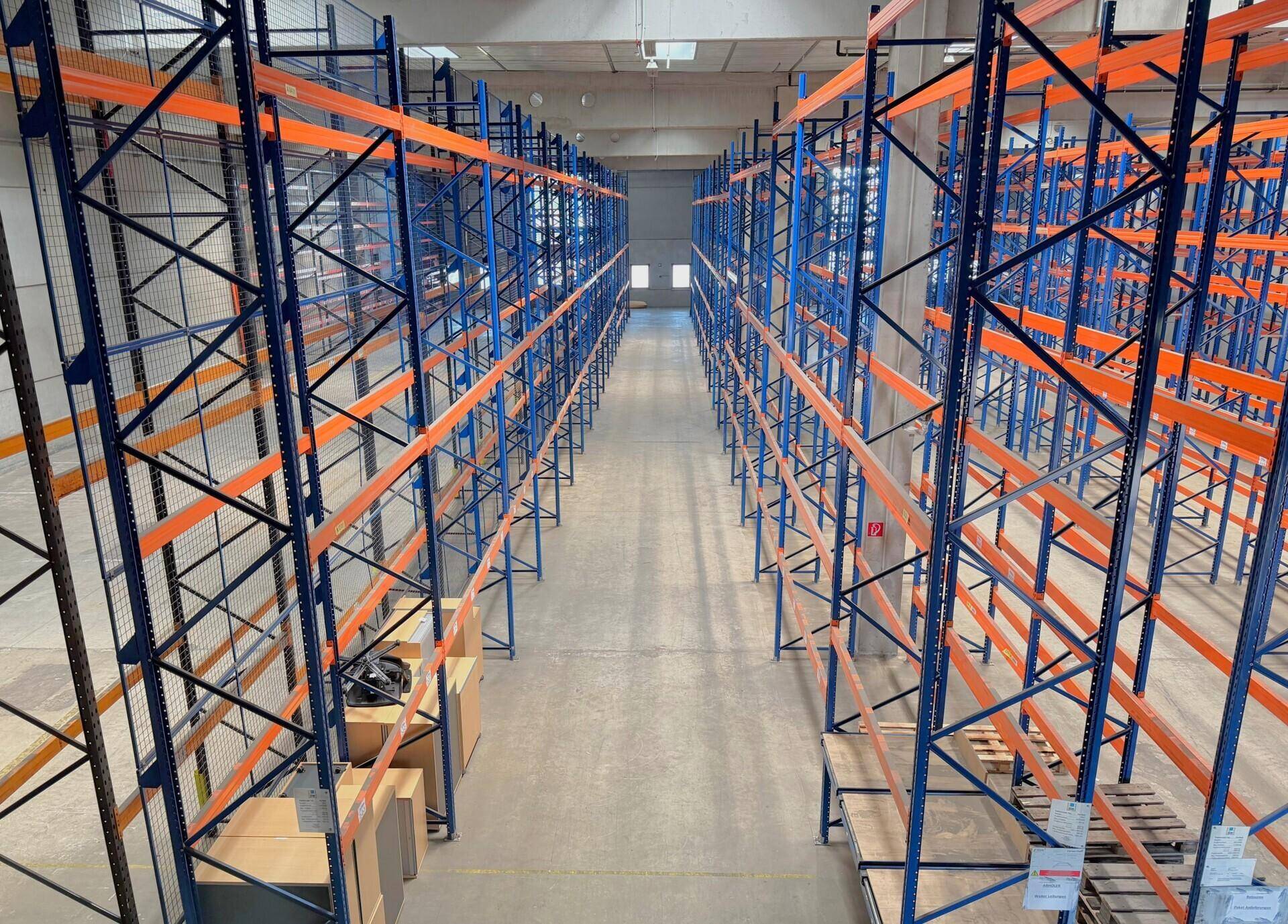 Weitläufige Reihen von leeren Lagerregalen in einer großen, gut beleuchteten Halle.