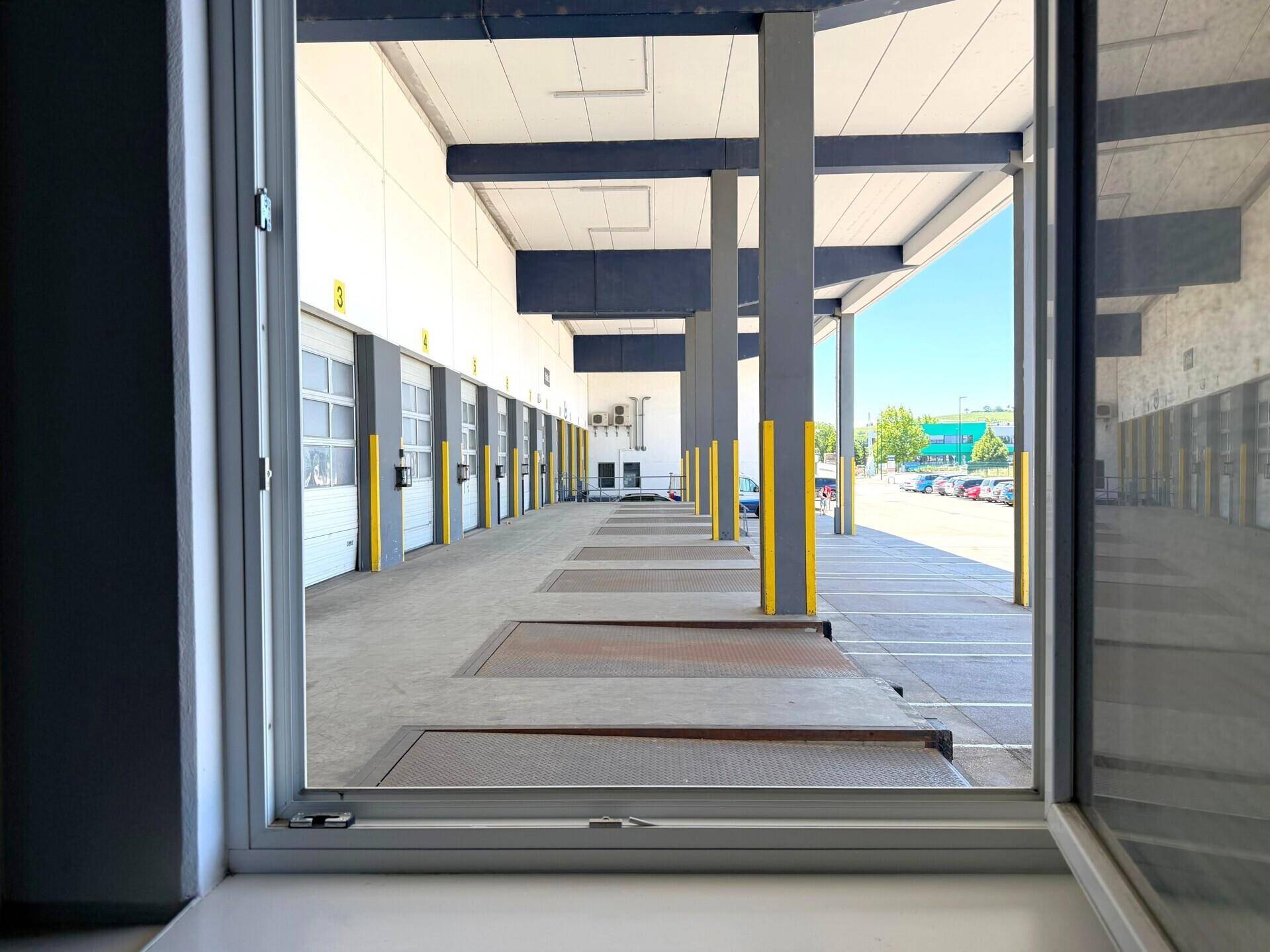 Blick aus einem Fenster auf die Laderampen und den Außenbereich der Lagerhalle.