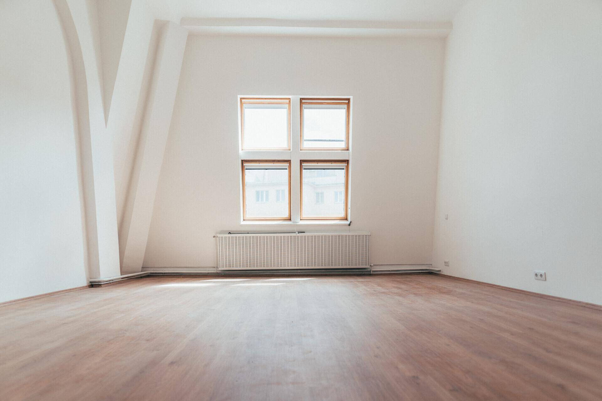 Geräumiger, heller Raum mit Laminatboden, weißen Wänden und einem großen Fensterbereich.