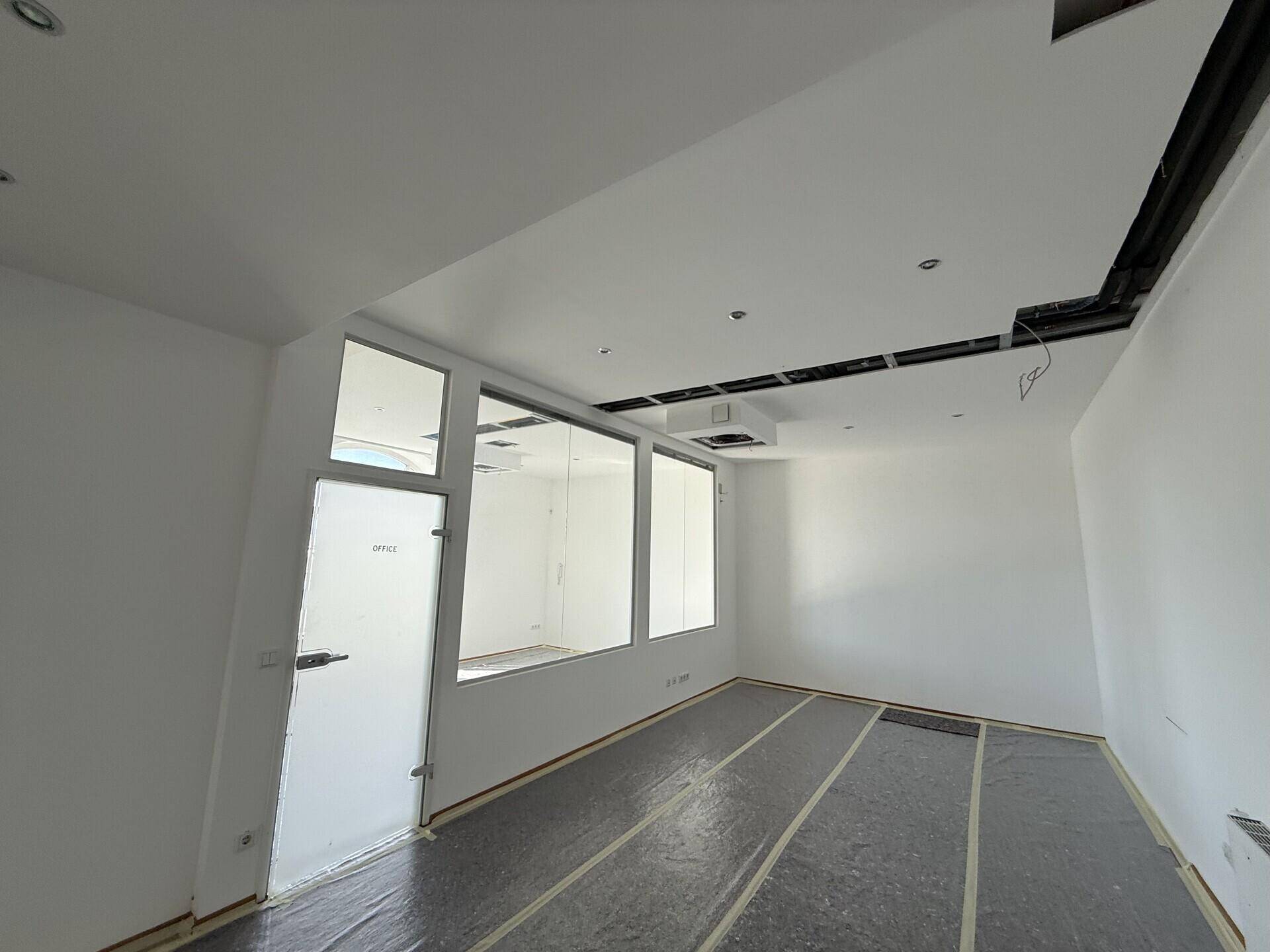 Leerer Büroraum mit Glasabtrennung und abgehängter Decke, vorbereitet für den weiteren Ausbau.