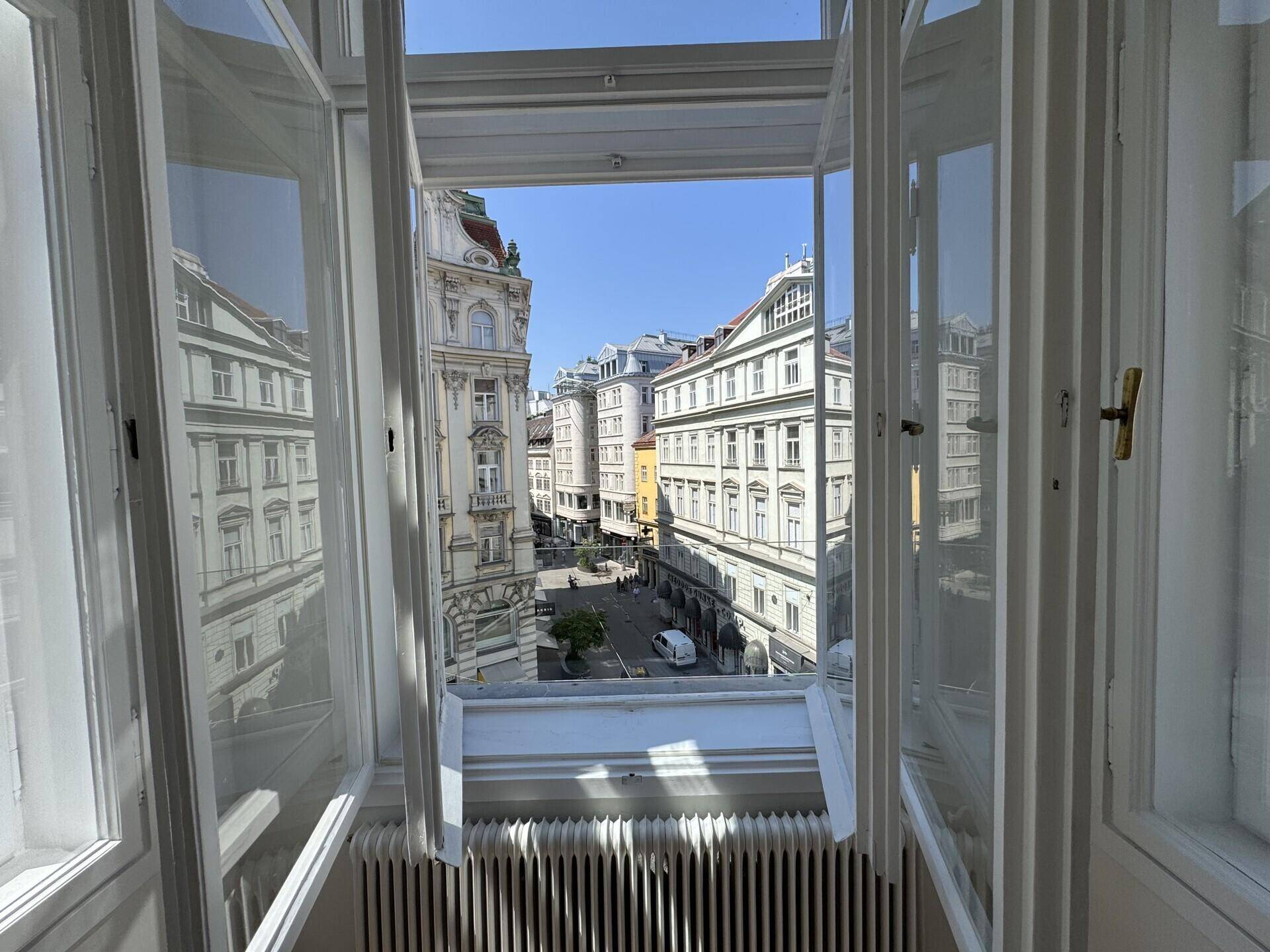 Blick aus einem Fenster auf die belebte Stadtstraße und die umliegenden historischen Gebäude.