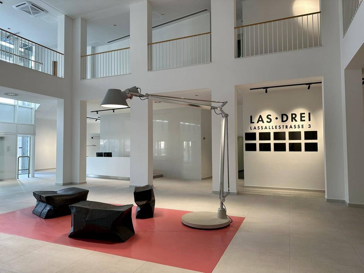 Moderne Lobby mit einer großen Design-Stehlampe, schwarzen Sitzwürfeln und hohen Decken.