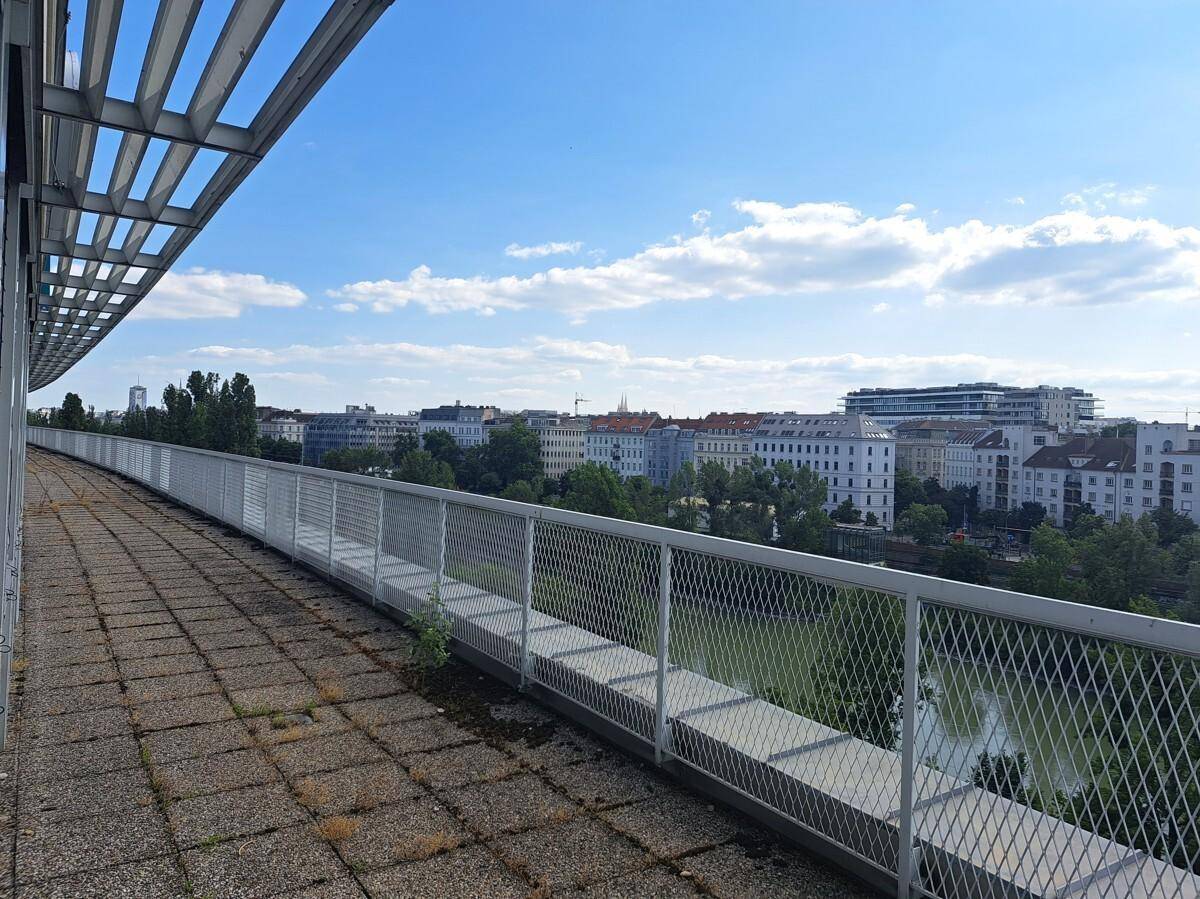 Langer Balkon mit Fliesenboden und Metallgeländer, bietet einen weiten Blick über die Stadt.
