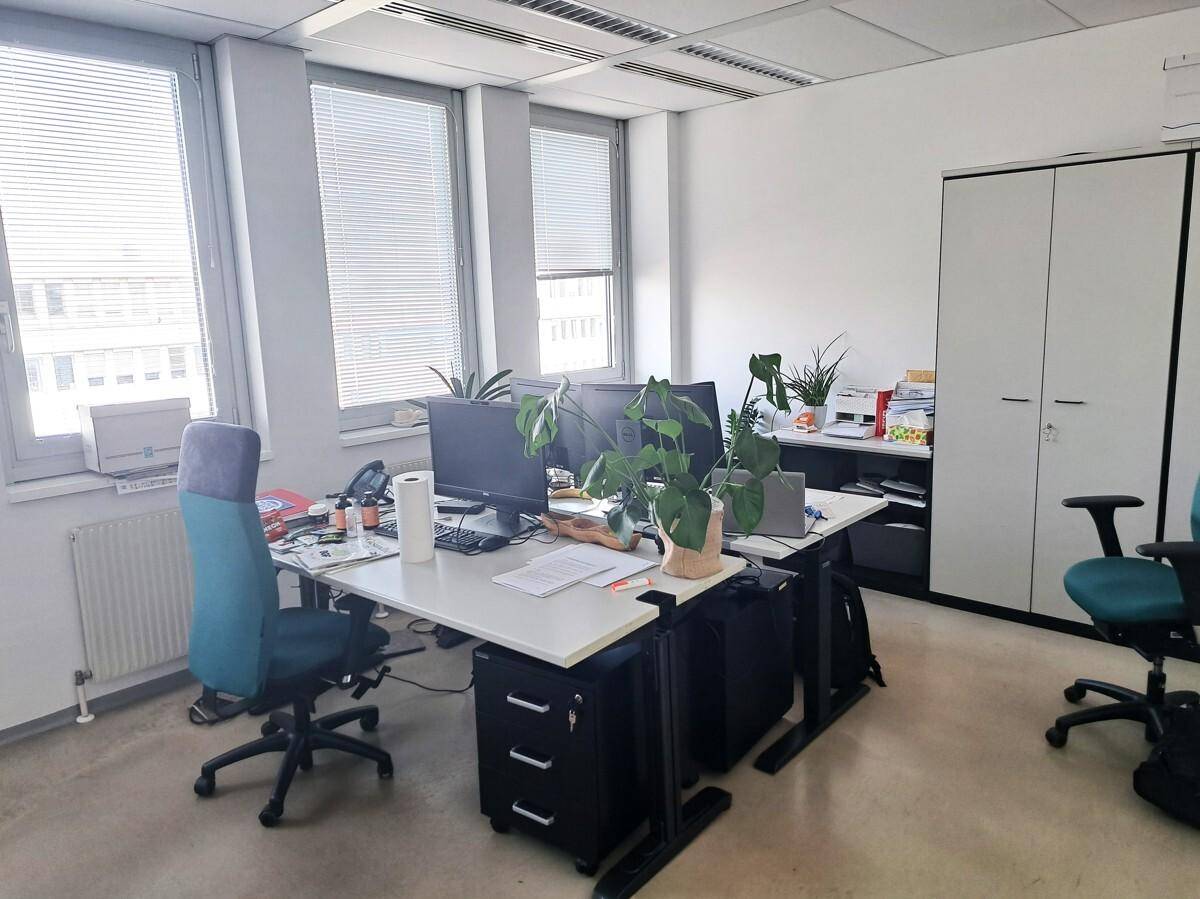 Geräumiger Bürobereich mit mehreren Schreibtischen, Stauraum und Jalousien an den Fenstern.