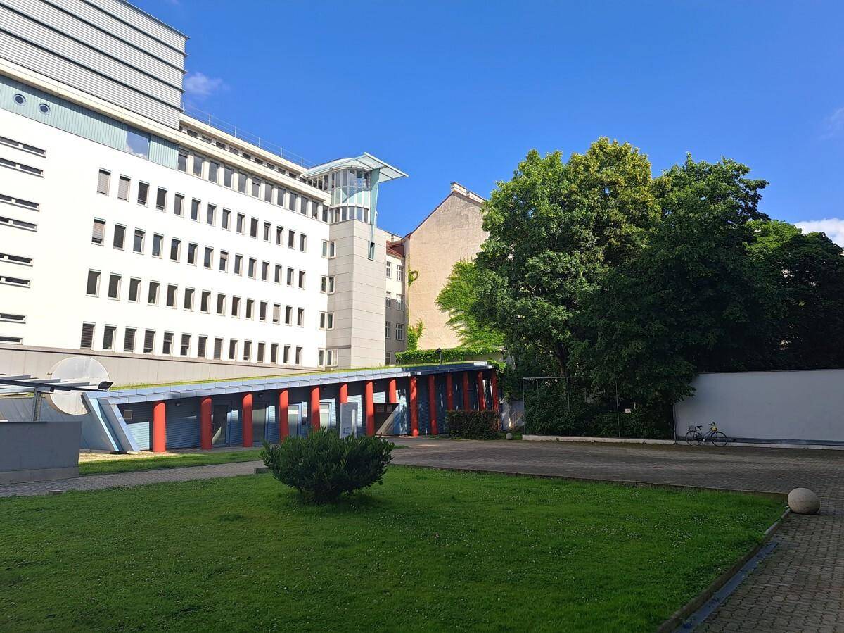 Außenansicht eines modernen Bürogebäudes mit Grünflächen und einem blauen Himmel.
