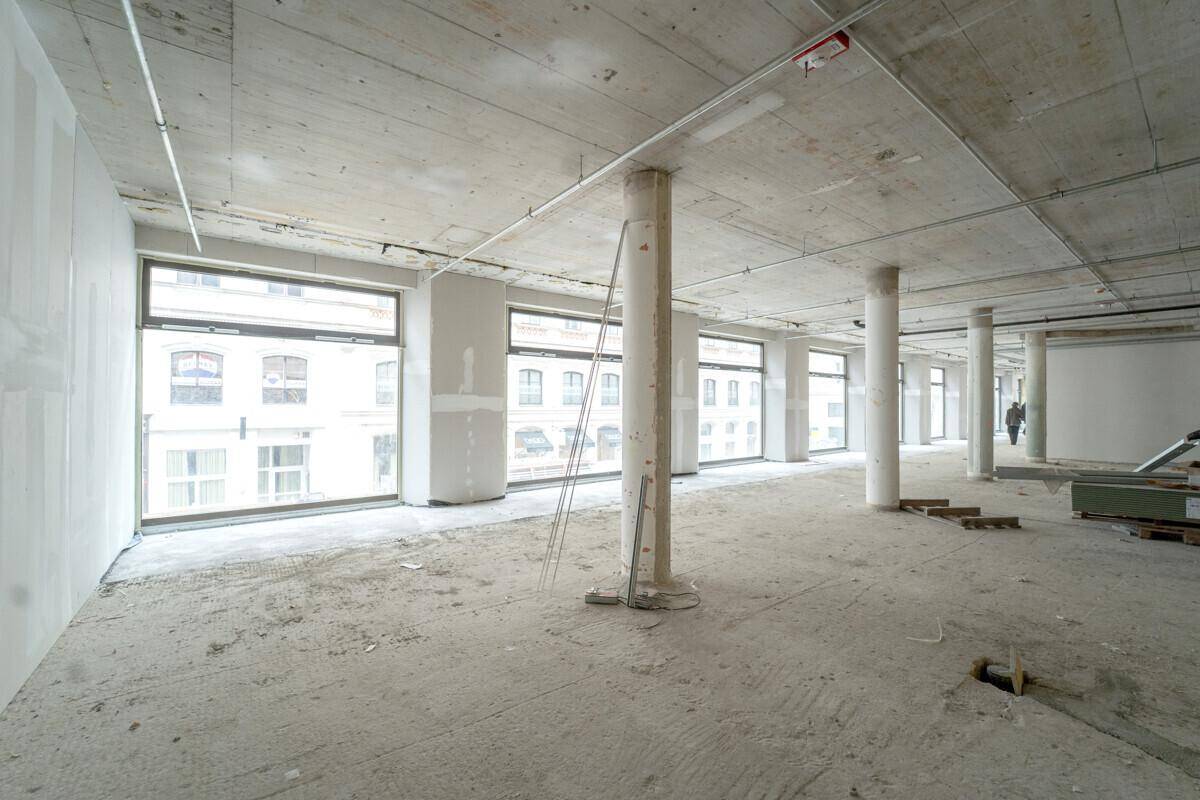 Rohbau-Bürofläche mit hohen Decken, großen Fenstern und einer weiten, offenen Raumgestaltung.