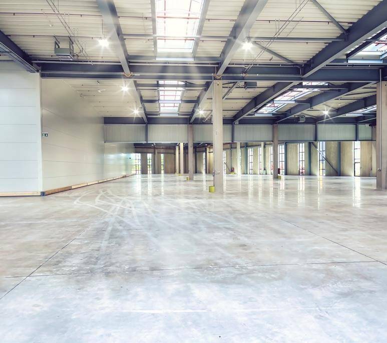 Helle und geräumige Lagerhalle mit poliertem Betonboden, hohen Decken und effizienter Beleuchtung.