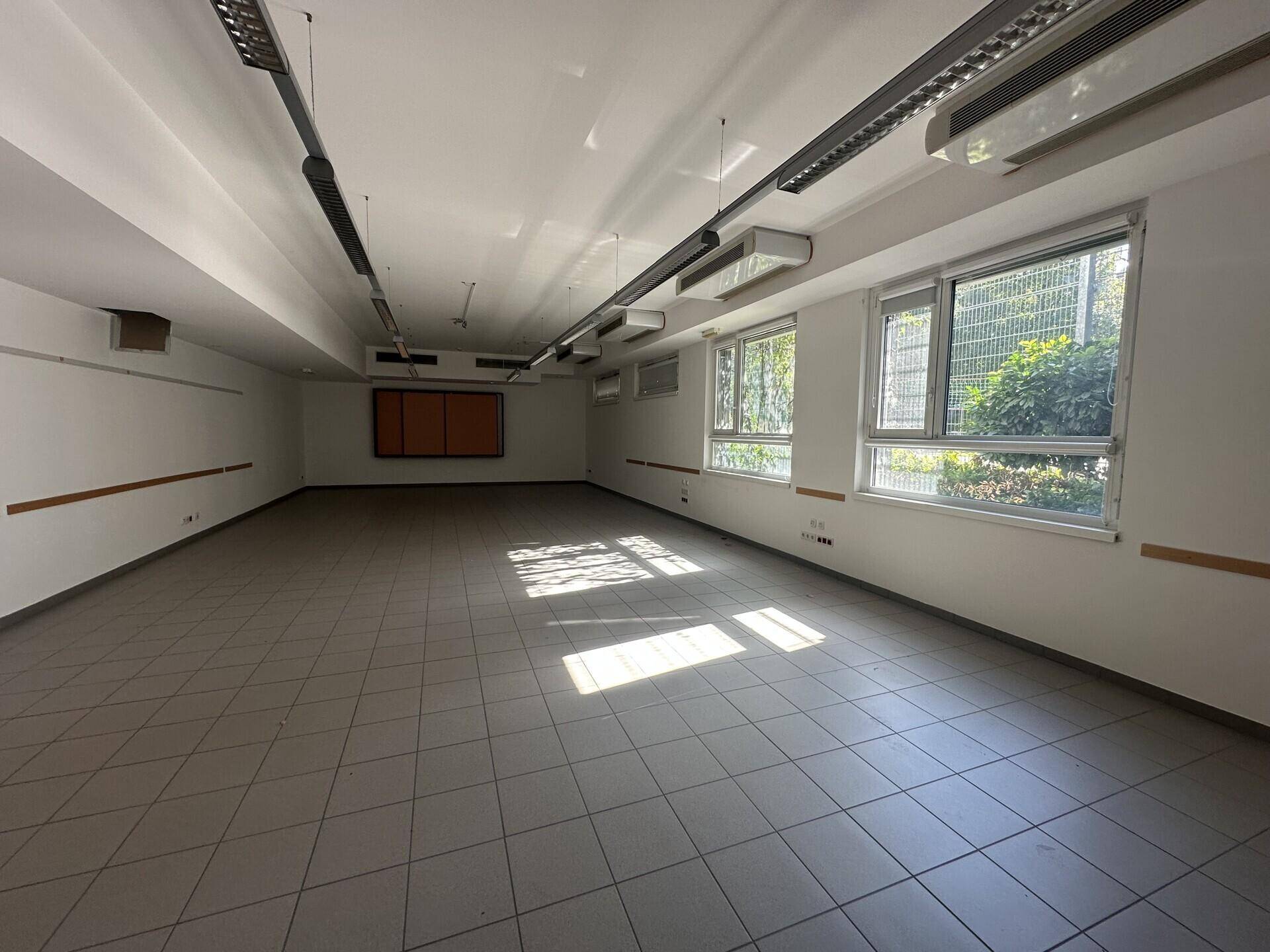 Langer, heller Büroraum mit Fliesenboden, vielen Fenstern und abgehängter Decke, bereit zur Einrichtung.