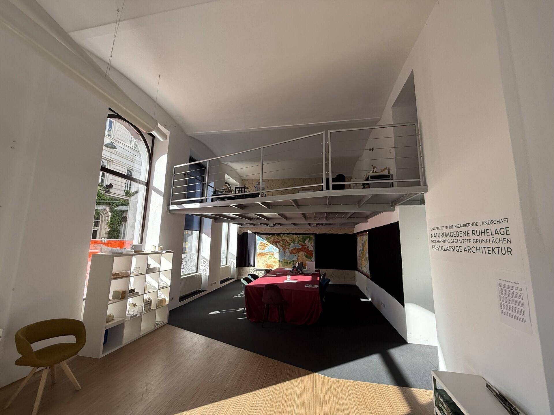 Heller Verkaufsraum mit hoher Decke, einer Galerie und großen Fenstern, die viel Tageslicht hereinlassen.