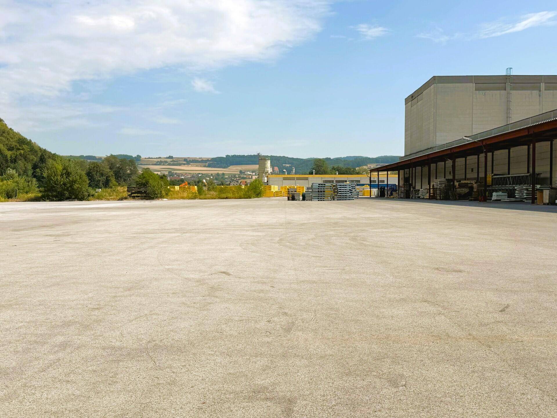 Weitläufiger asphaltierter Vorplatz mit Blick auf die umliegende Landschaft und Industrieanlagen.