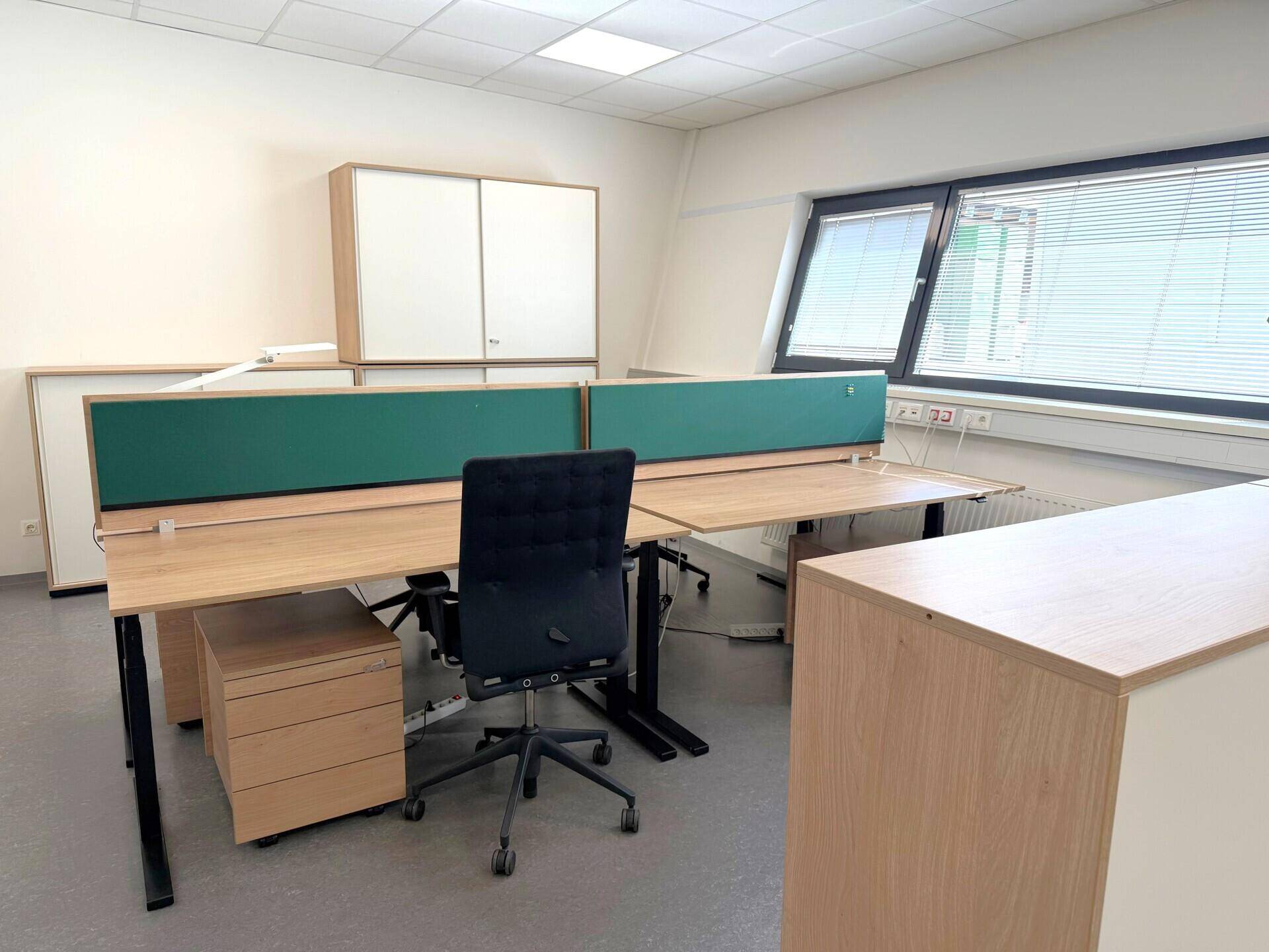 Moderner Einzelarbeitsplatz in einem Büro mit Holzschreibtisch und Stauraum.