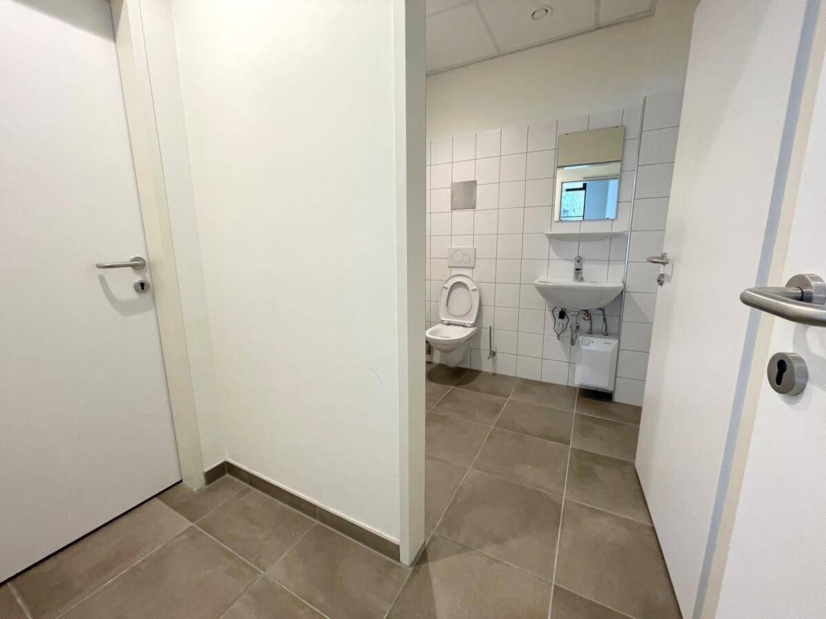 Sauberer Toilettenraum mit Fliesenboden, Waschbecken und Spiegel, in gutem Zustand.