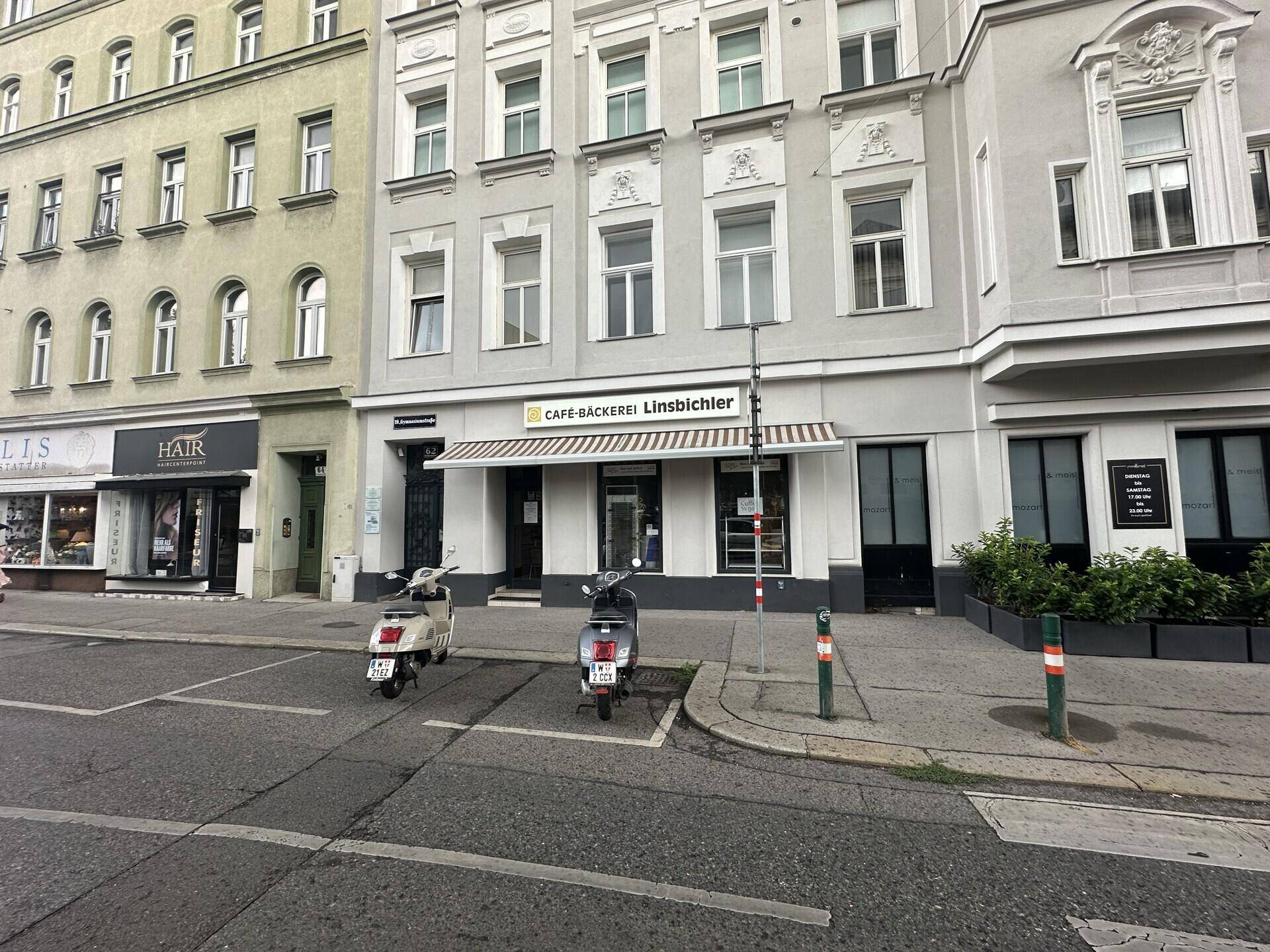 Weitwinkelansicht der historischen Straße mit einer Bäckerei und geparkten Rollern.