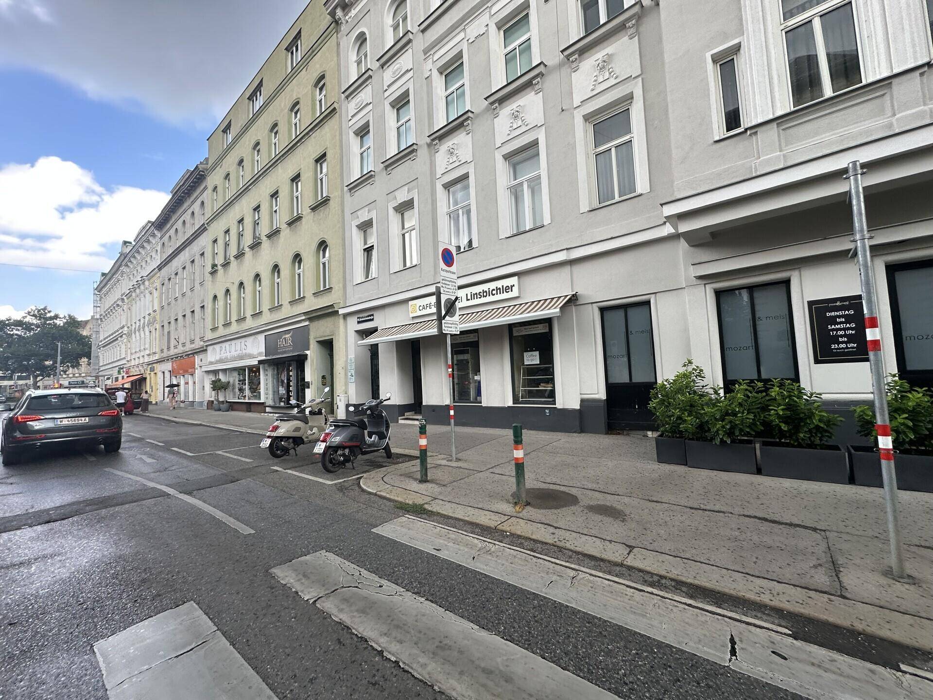 Panoramablick auf eine belebte Stadtstraße mit historischen Gebäuden und Geschäften.