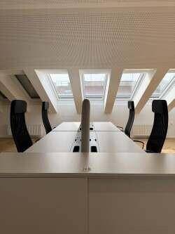 Großraumbüro mit langen Schreibtischen, ergonomischen Stühlen und mehreren Dachfenstern für viel Licht.