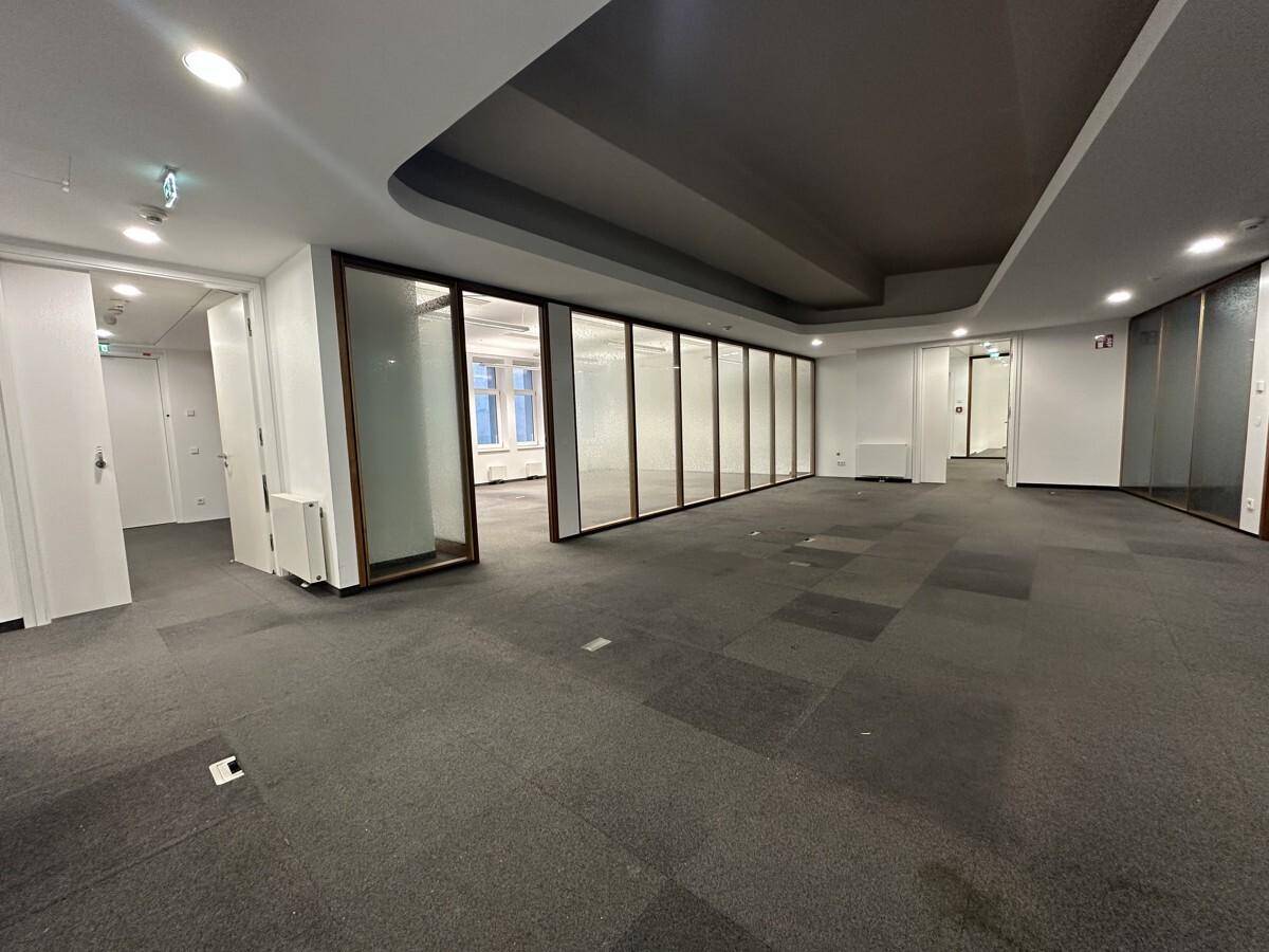Geräumiger Bürobereich mit Teppichboden, Glaswänden und moderner Beleuchtung, ideal für flexible Arbeitsplatzgestaltung.