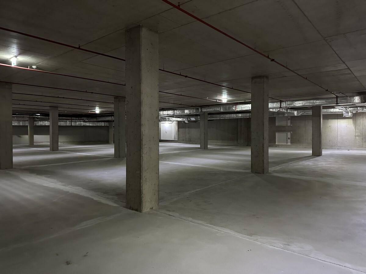 Leere Tiefgarage mit Betonpfeilern und sichtbaren Installationen an der Decke.
