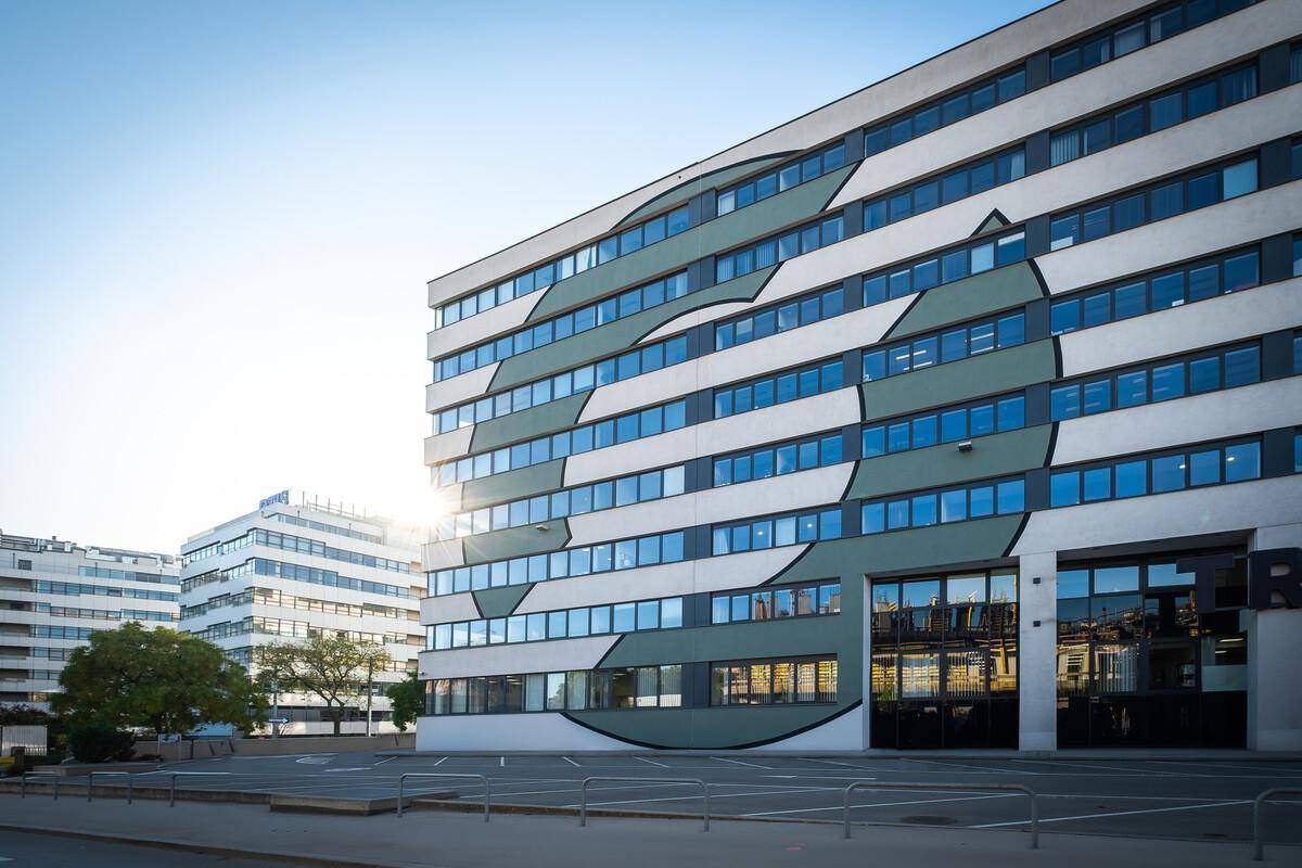 Detailansicht der modernen Gebäudefassade mit einzigartigem Muster und großen Fensterfronten bei Sonnenlicht.