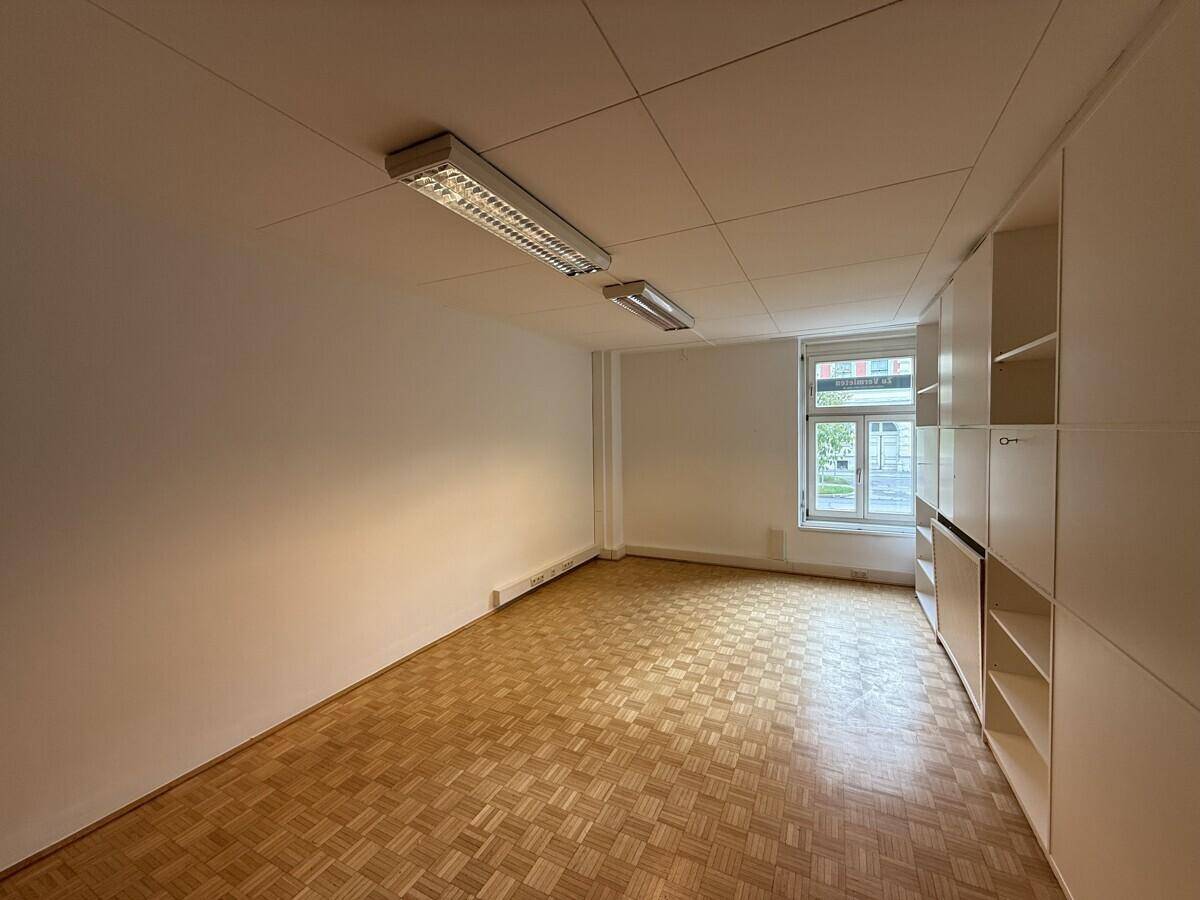 Helles Büro mit Parkettboden und integrierten Regalen, bietet viel Stauraum und Arbeitsfläche.