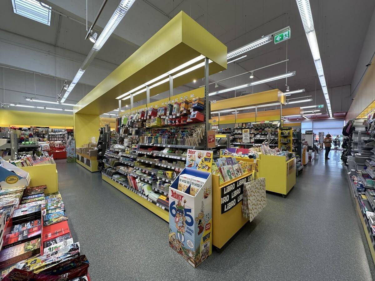 Heller Verkaufsraum mit gelben Akzenten an den Regalen, präsentiert eine Vielzahl von Produkten.