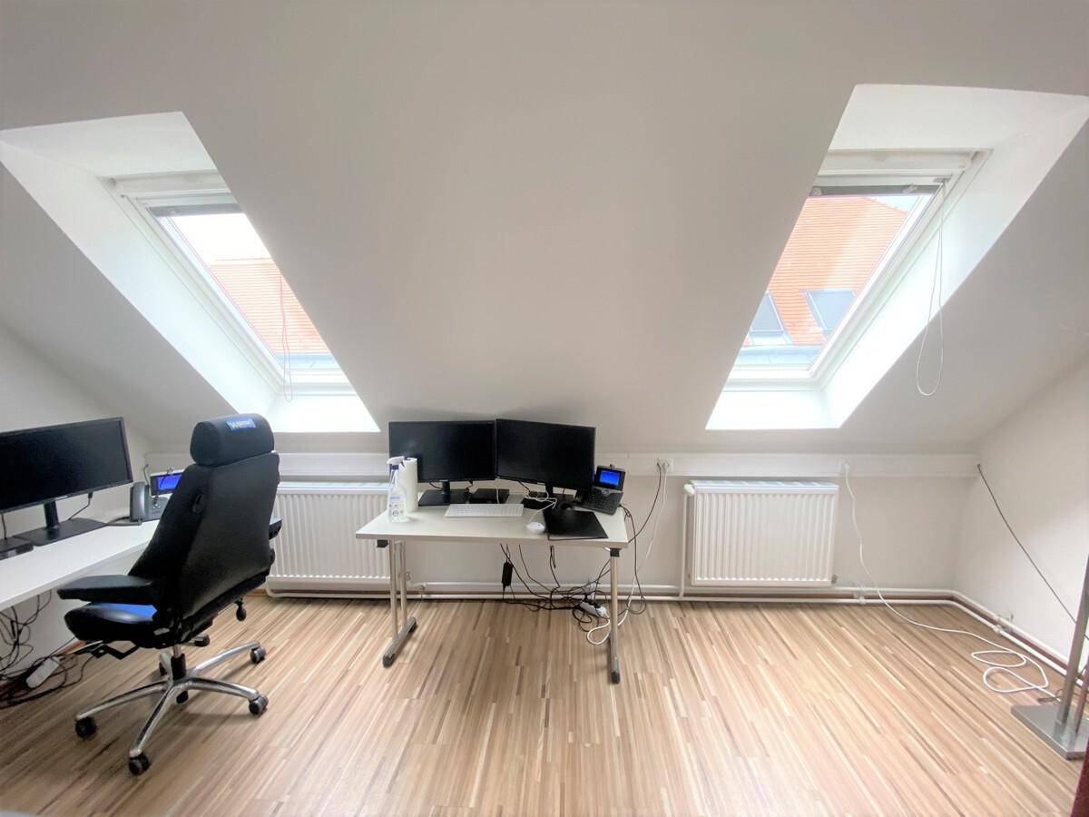 Dachgeschossbüro mit schrägen Wänden, Dachfenstern und Arbeitsplätzen mit Computern.