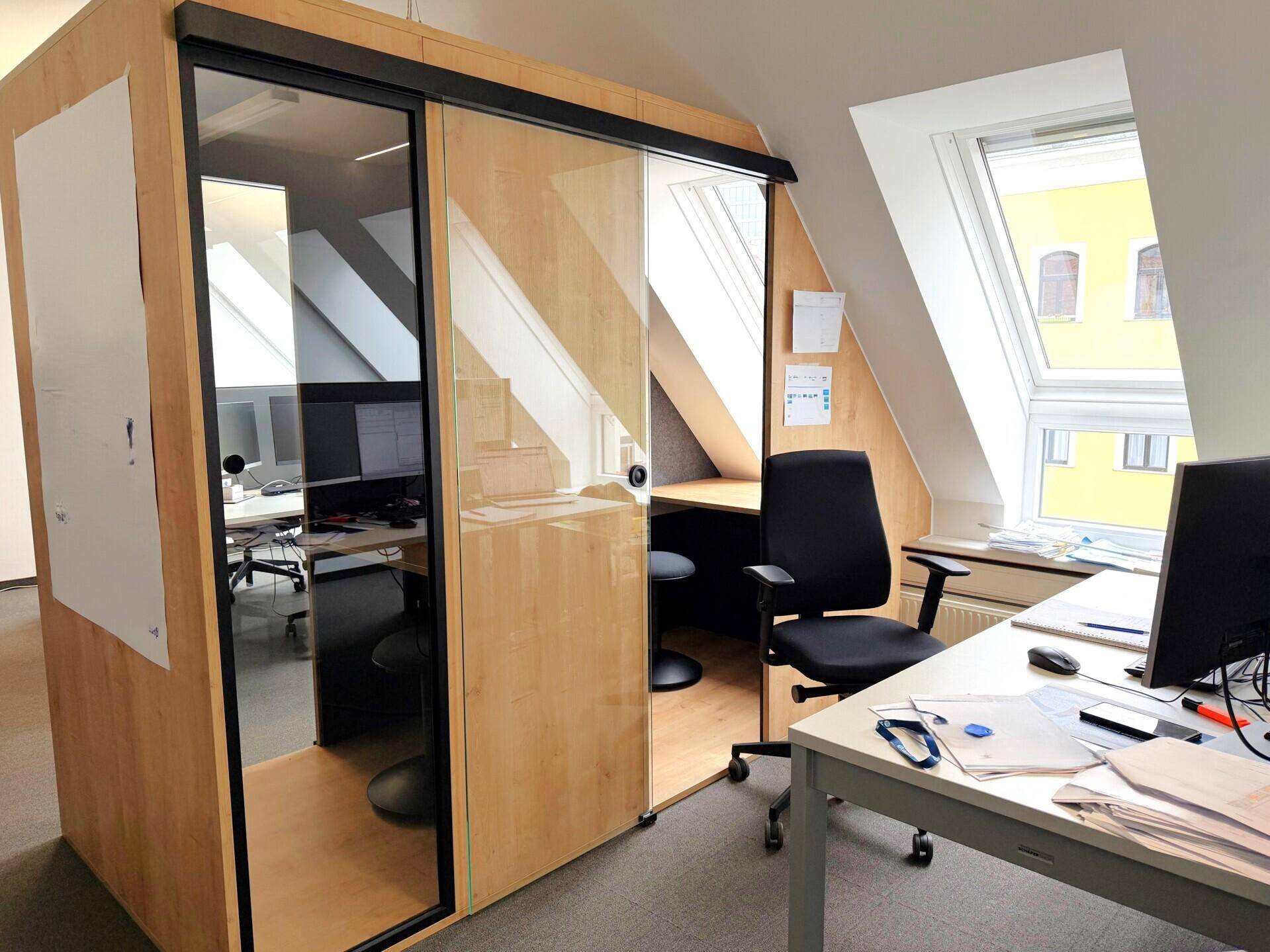 Kleiner Arbeitsbereich mit Holztisch, Hocker und Dachfenster, ideal für fokussierte Aufgaben.