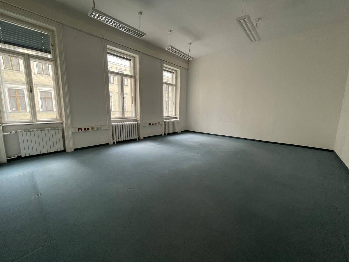 Geräumiger, leerer Raum mit Teppichboden und drei großen Fenstern, ideal als Bürofläche.