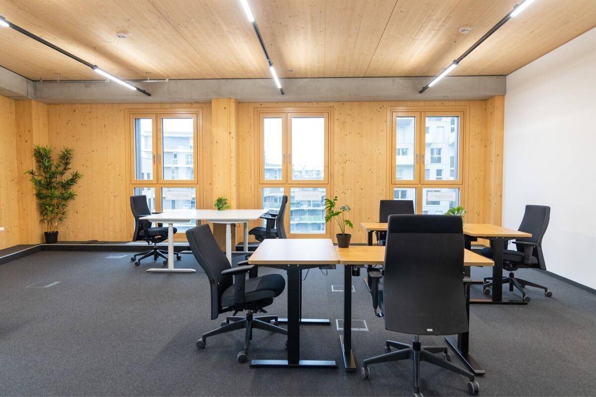 Geräumiges Großraumbüro mit vielen Arbeitsplätzen, modernen Bürostühlen und Holzelementen.
