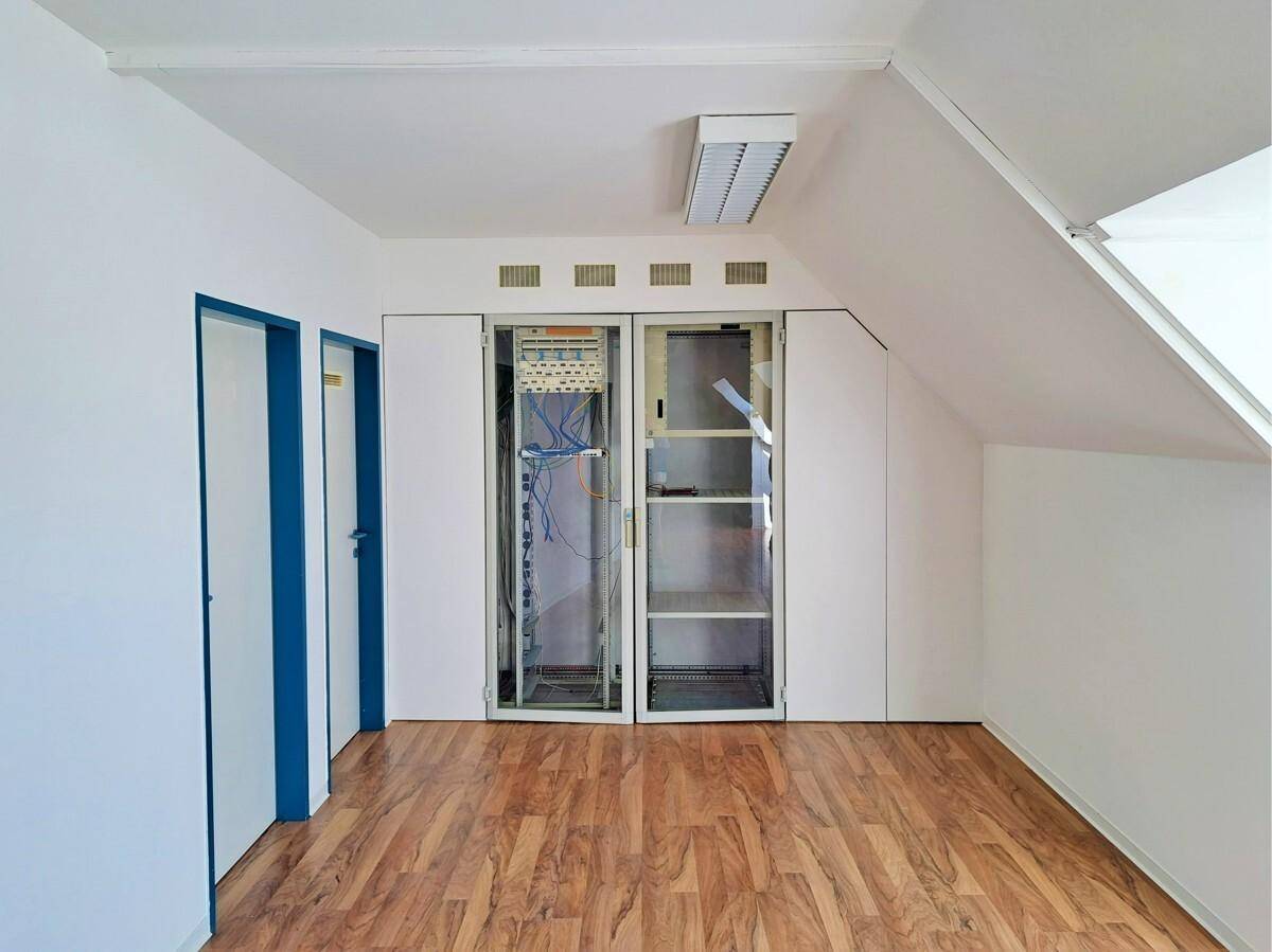 Raum mit Dachschräge, Laminatboden und zwei Serverschränken, ideal für technische Installationen.