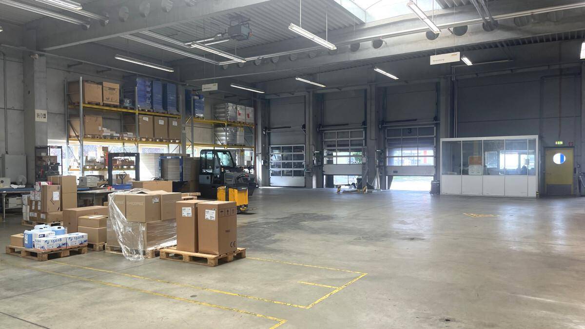 Lagerhalle mit mehreren Rolltoren für den Warenumschlag und einem kleinen Büro im Hintergrund.