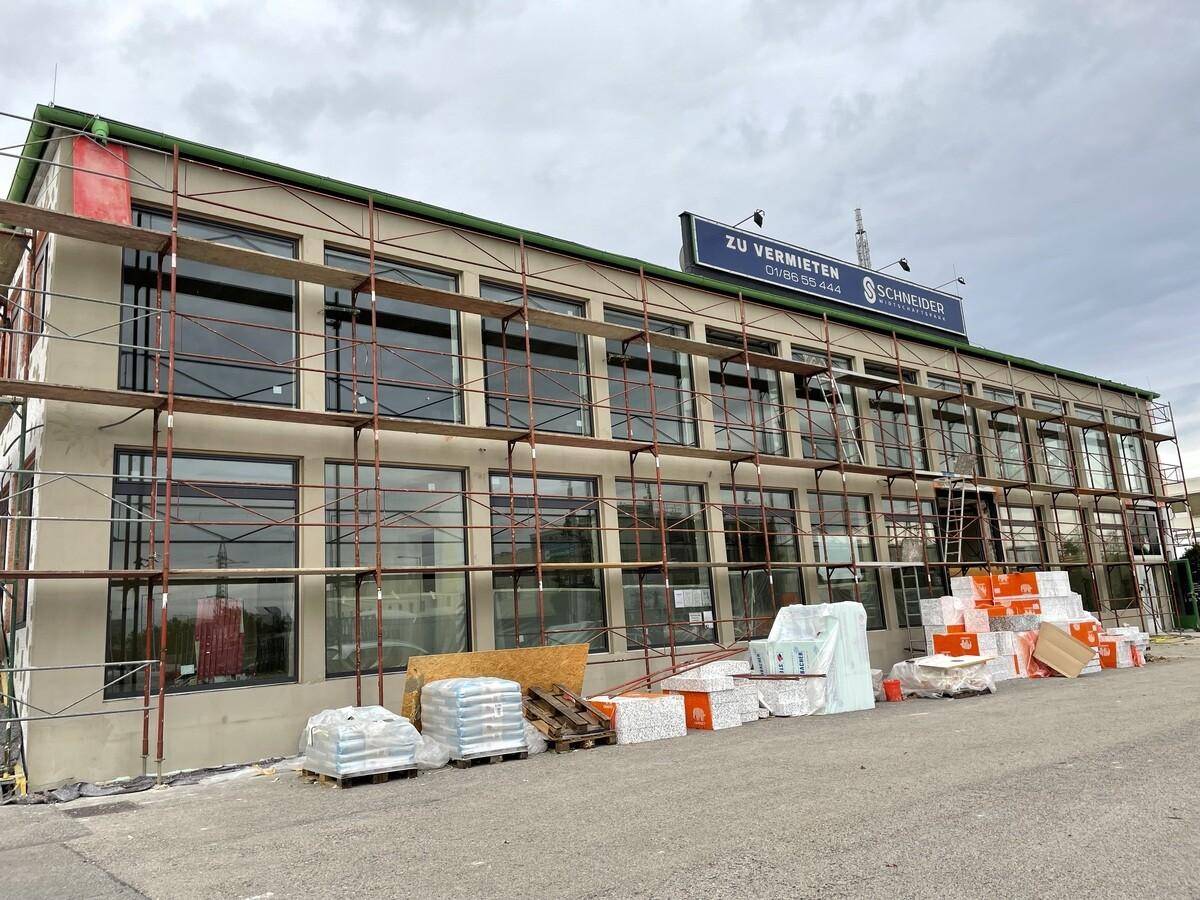 Gebäude im Bau mit Gerüst und großen Fensterfronten, bereit für den Innenausbau.