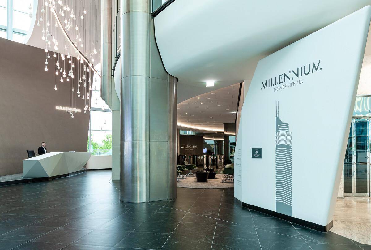 Elegante Lobby mit hoher Decke, moderner Rezeption und einer großen Säule, die das Gebäude Millennium Tower bewirbt.