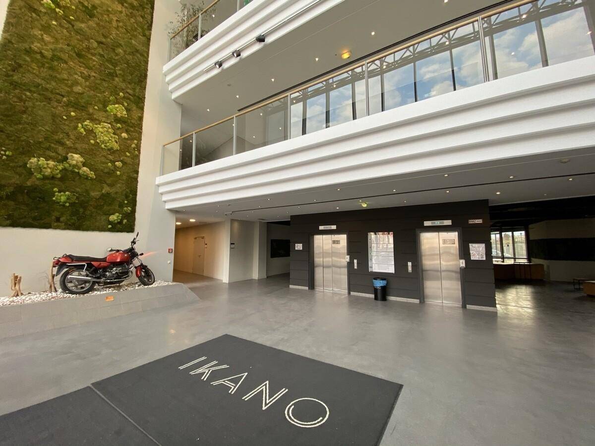 Geräumige moderne Lobby mit hohen Decken, Mooswand und Aufzügen, inklusive dekorativem Motorrad.
