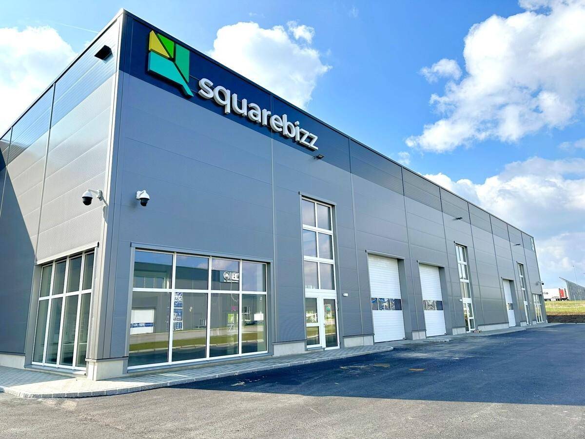 Ansicht eines modernen Gewerbegebäudes mit großen Glasflächen und Rolltoren.