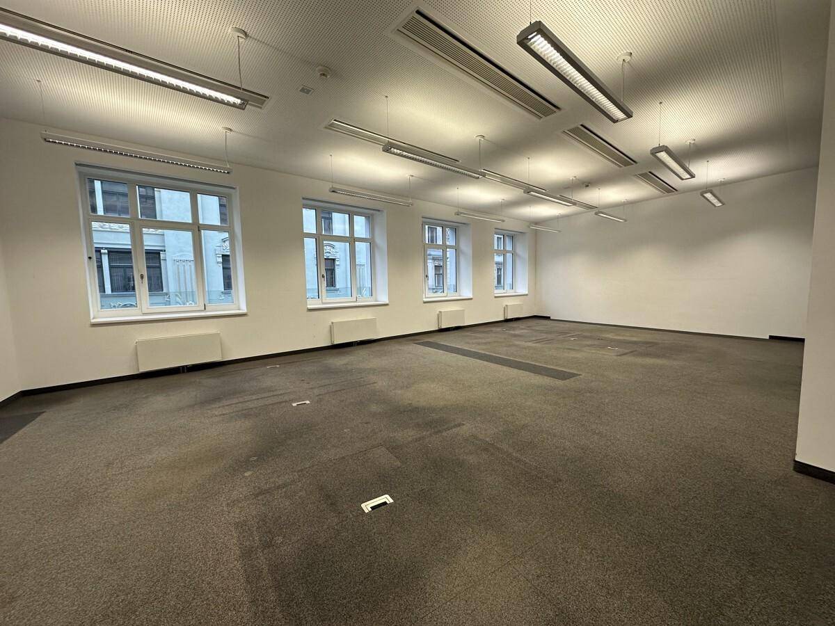 Großer Büroraum mit Teppichboden, mehreren Fenstern und moderner Beleuchtung, ideal für flexible Arbeitsplatzlösungen.