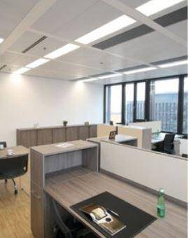 Helles und offenes Büro mit modernen Arbeitsplätzen, Holzmöbeln und großen Fenstern.