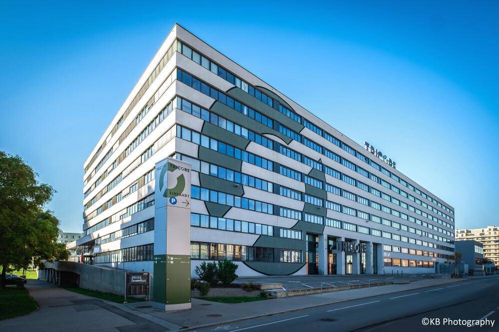 Modernes Bürogebäude mit markanter Fassadengestaltung und vielen Fenstern unter blauem Himmel.