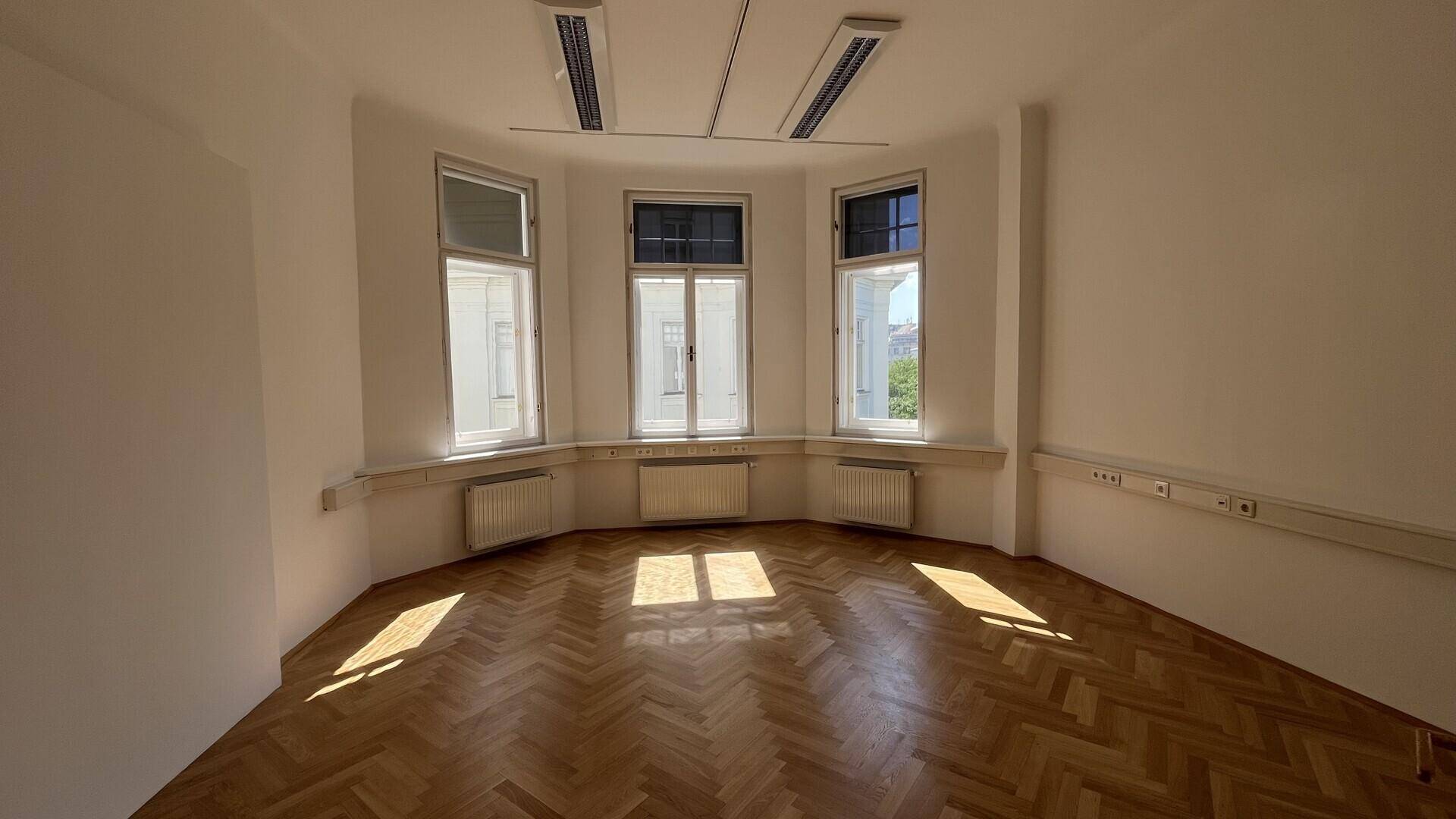 Geräumiges Büro mit Erkerfenstern, Fischgrätparkett und viel Tageslicht, sonnendurchflutet.