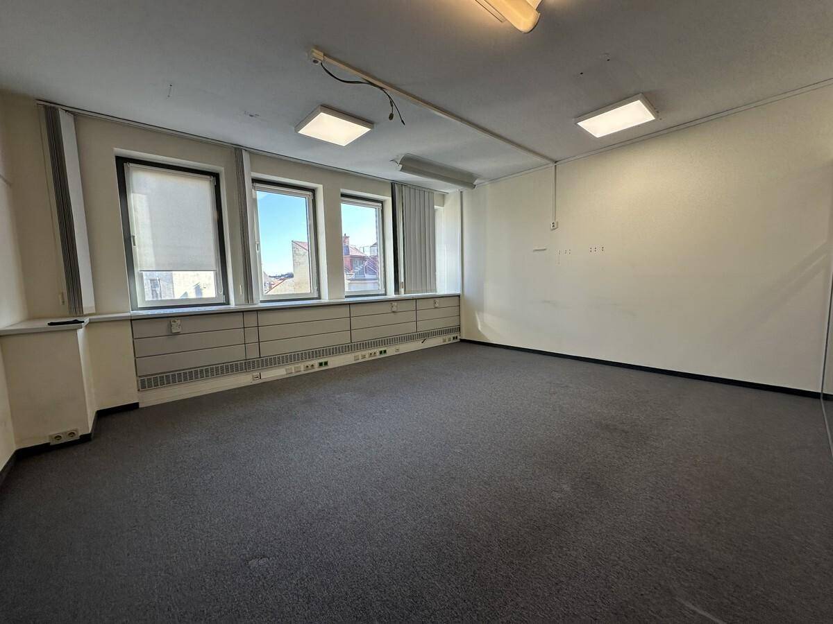 Geräumiges Büro mit Teppichboden, hellen Wänden und mehreren Fenstern, die für eine gute Belichtung sorgen.