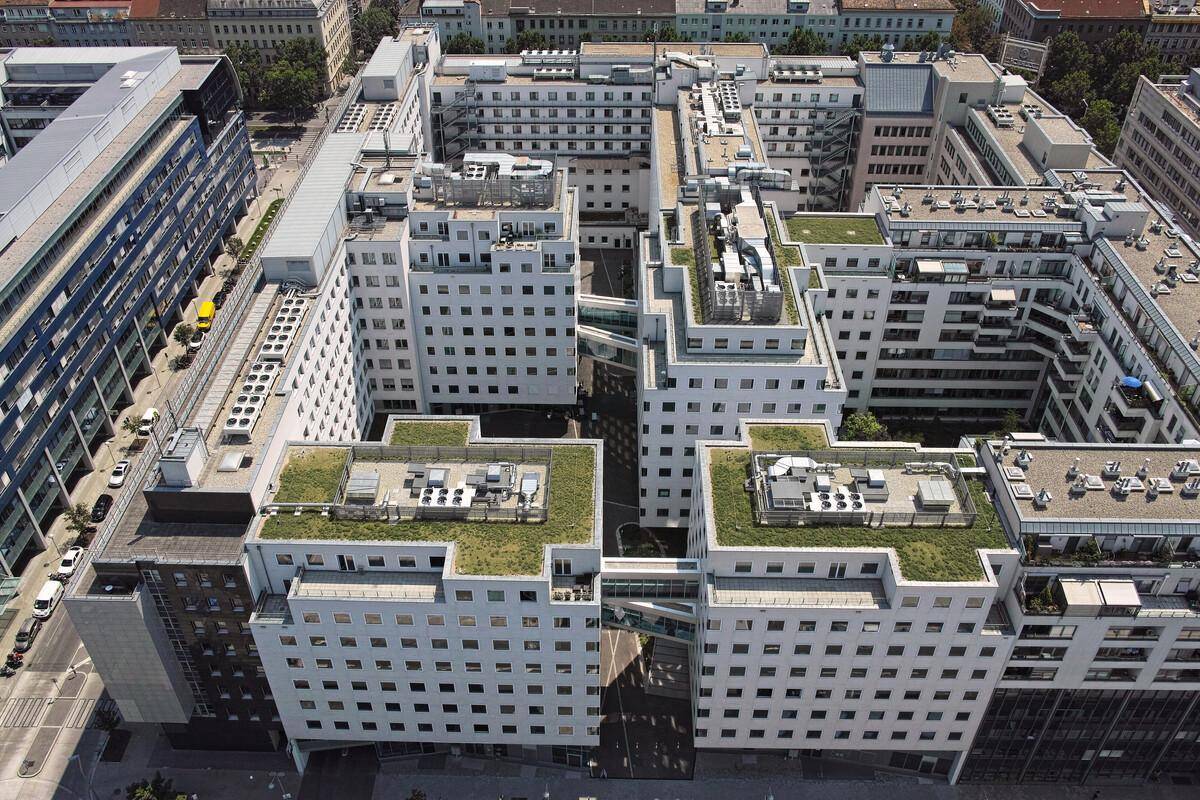 Luftaufnahme eines modernen Gebäudekomplexes mit mehreren Gebäudeteilen und begrünten Dächern.