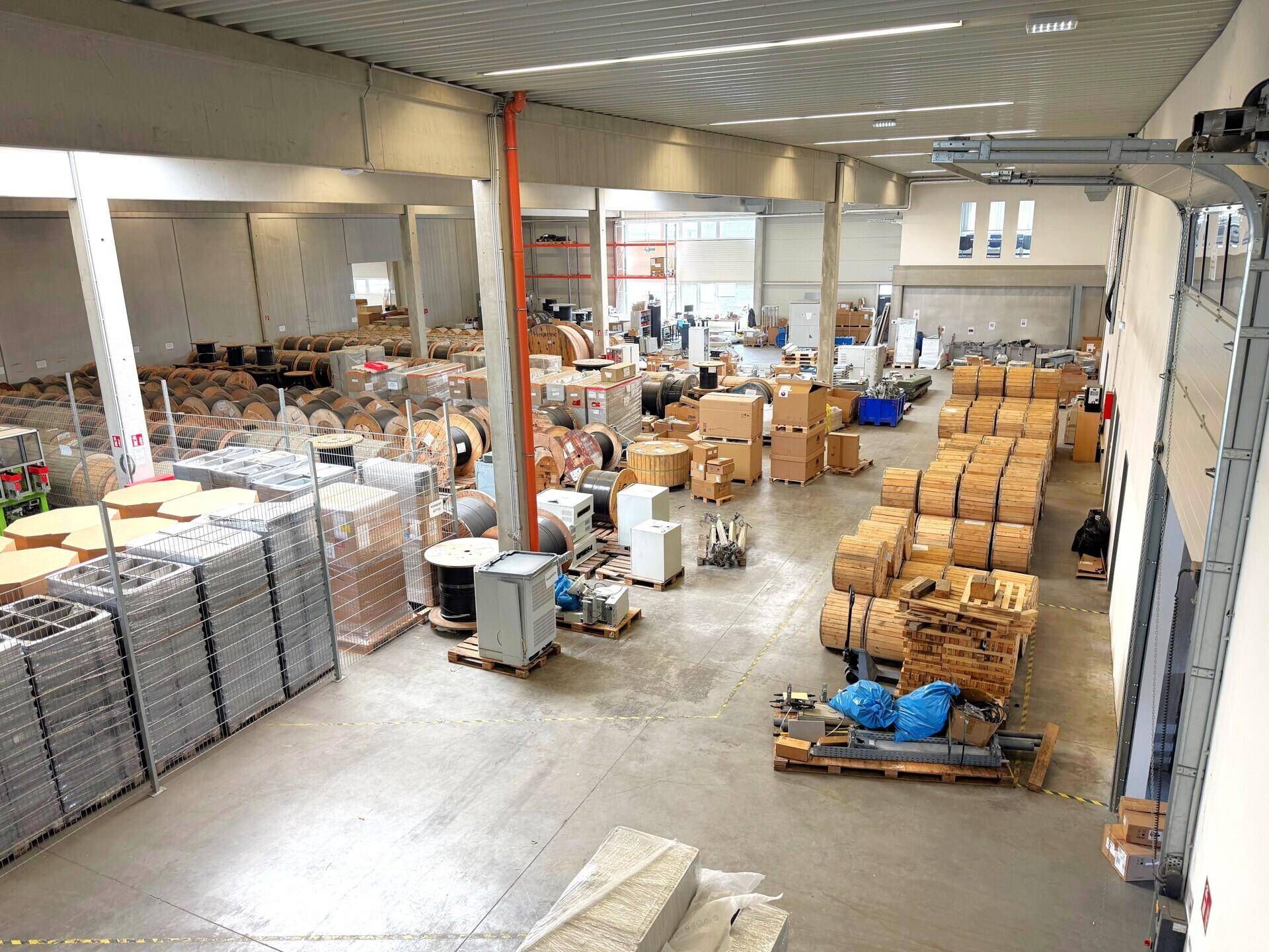 Große Lagerhalle mit hohen Decken, Betonboden und zahlreichen Waren auf Paletten.