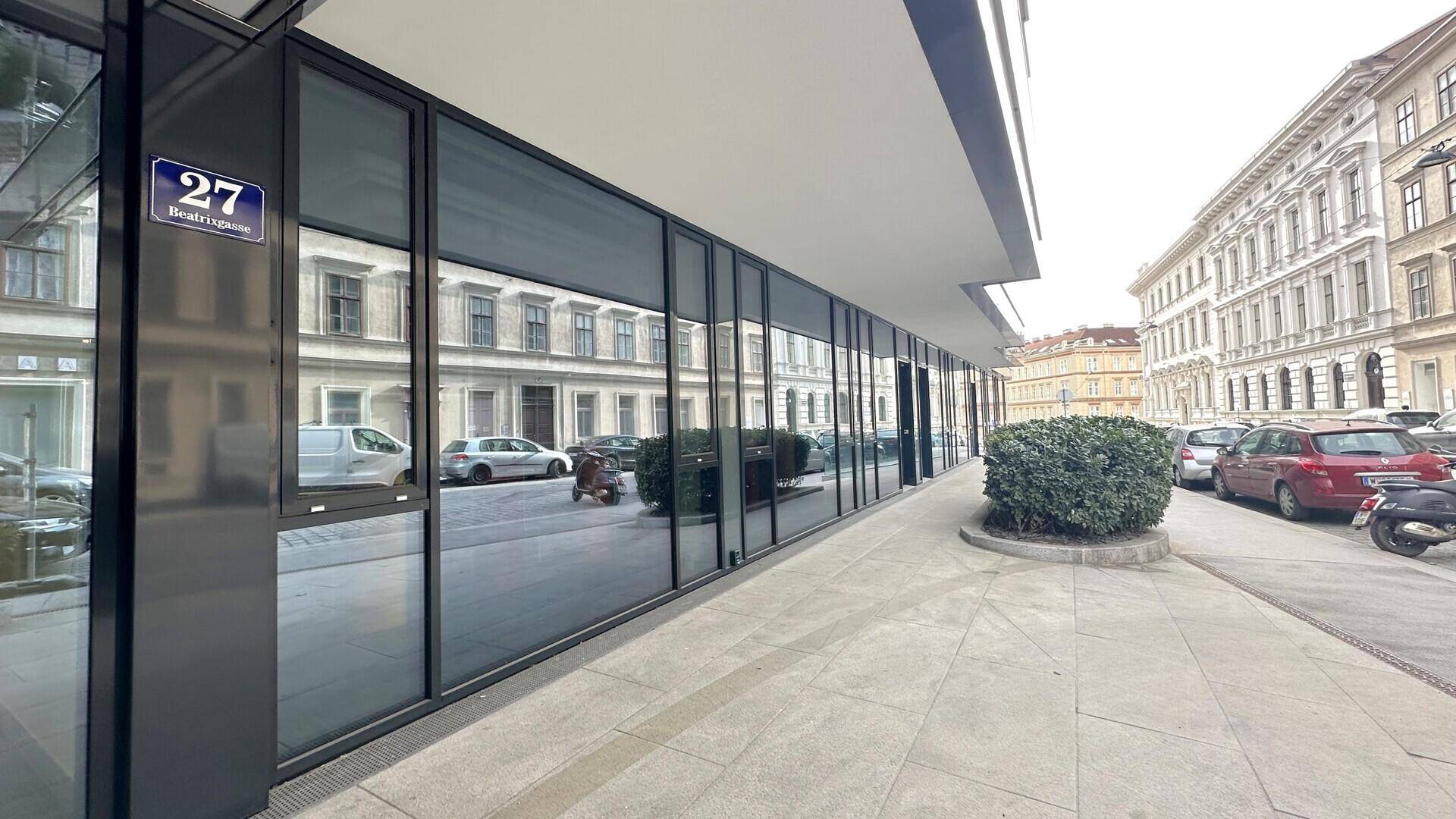 Die moderne Geschäftsfassade mit großen Fenstern spiegelt die gegenüberliegenden historischen Gebäude wider.