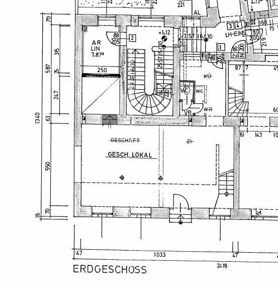 Grundriss des Erdgeschosses mit einem großen Geschäftsraum, Treppenhaus und sanitären Einrichtungen.