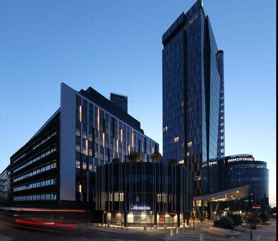 Beeindruckende moderne Bürogebäude bei Sonnenuntergang mit beleuchteten Fassaden und städtischem Flair.