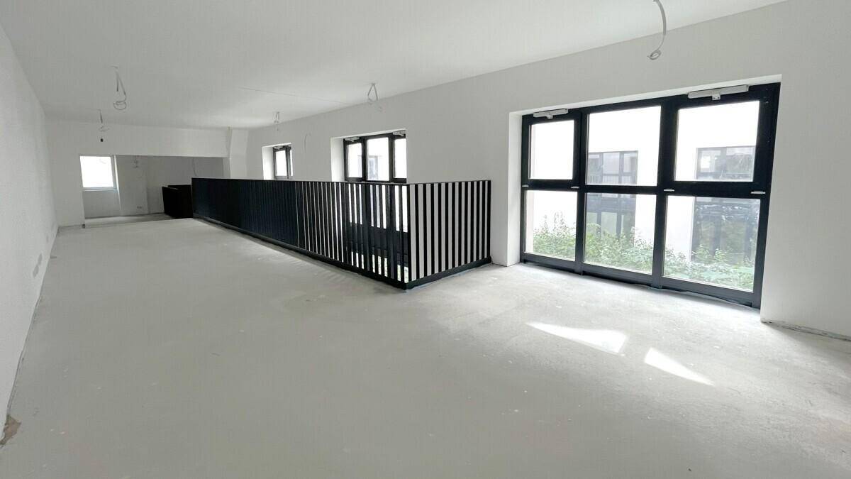 Galerieebene mit schwarzem Geländer, großen Fenstern und Blick auf den unteren Bereich.
