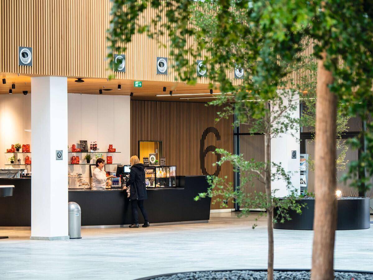 Moderner Café-Bereich mit Holzwänden, schwarzer Theke und Sitzgelegenheiten.