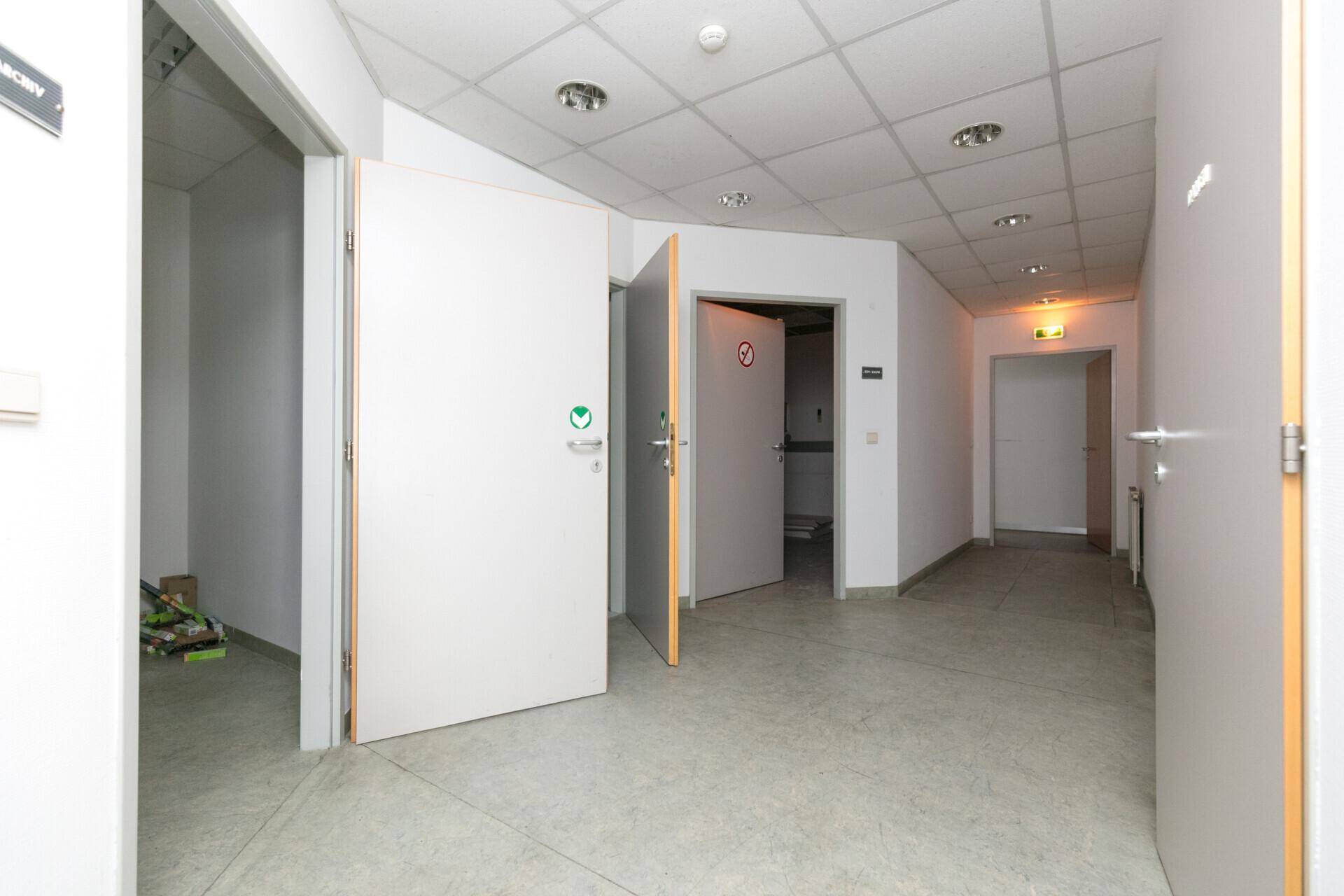 Heller Flur mit mehreren Türen, Fliesenboden und Deckenbeleuchtung, führt zu weiteren Räumen.