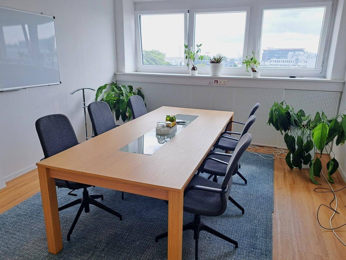Konferenzraum mit großem Holztisch, bequemen Stühlen und Blick nach draußen.
